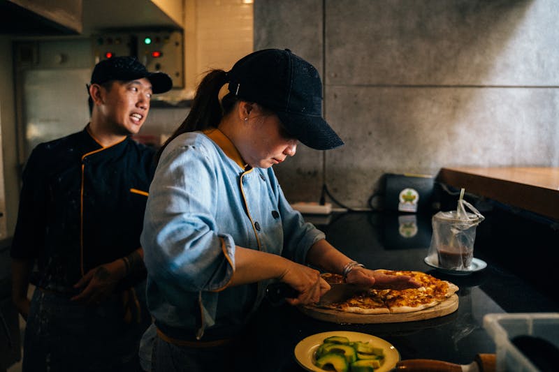 Kitchen brigade team preparing pizzas in professional kitchen